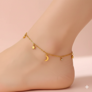 Gold anklet with star, moon, and heart charms on a foot against a beige background